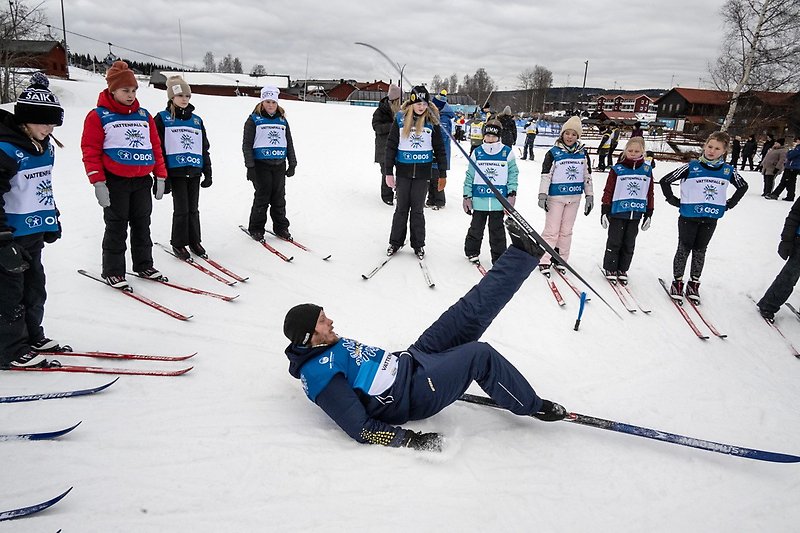 Barn på längdskidor, en ledare visar hur de ska ta sig upp om de ramlar. Foto: Ulf Palm.