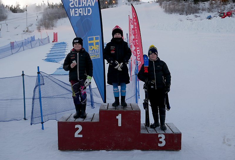 Tre unga killar står på prispallen och håller plaketter i handen efter distriktsmästerskap i slalom.